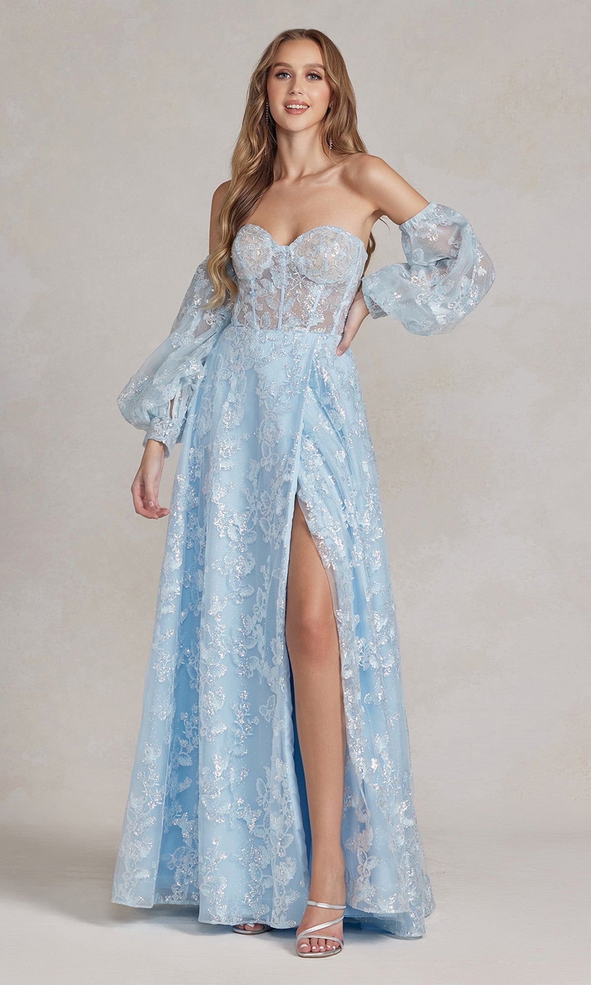 A woman stands elegantly in front of a neutral background, wearing the Long Puff-Sleeve Prom Dress with a sheer bodice, styled with removable long sleeves and a thigh-high slit in light blue lace.